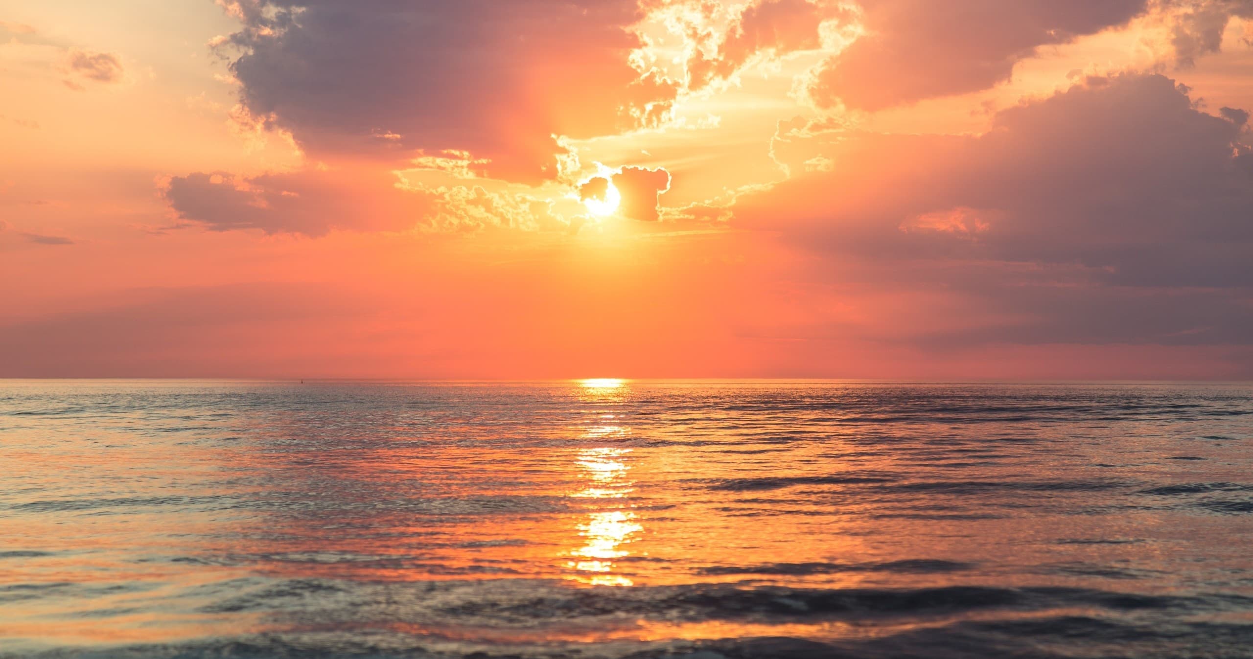 Vibrant ocean sunset over calm sea with reflective water