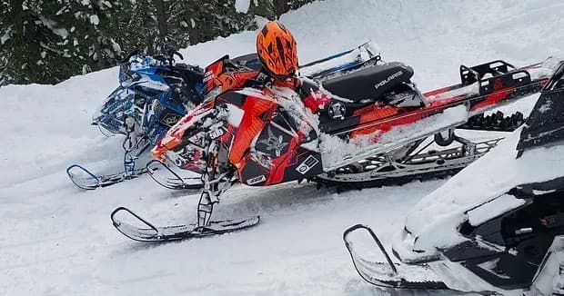 Snowmobilers riding powder near Tahoe forest during winter tour