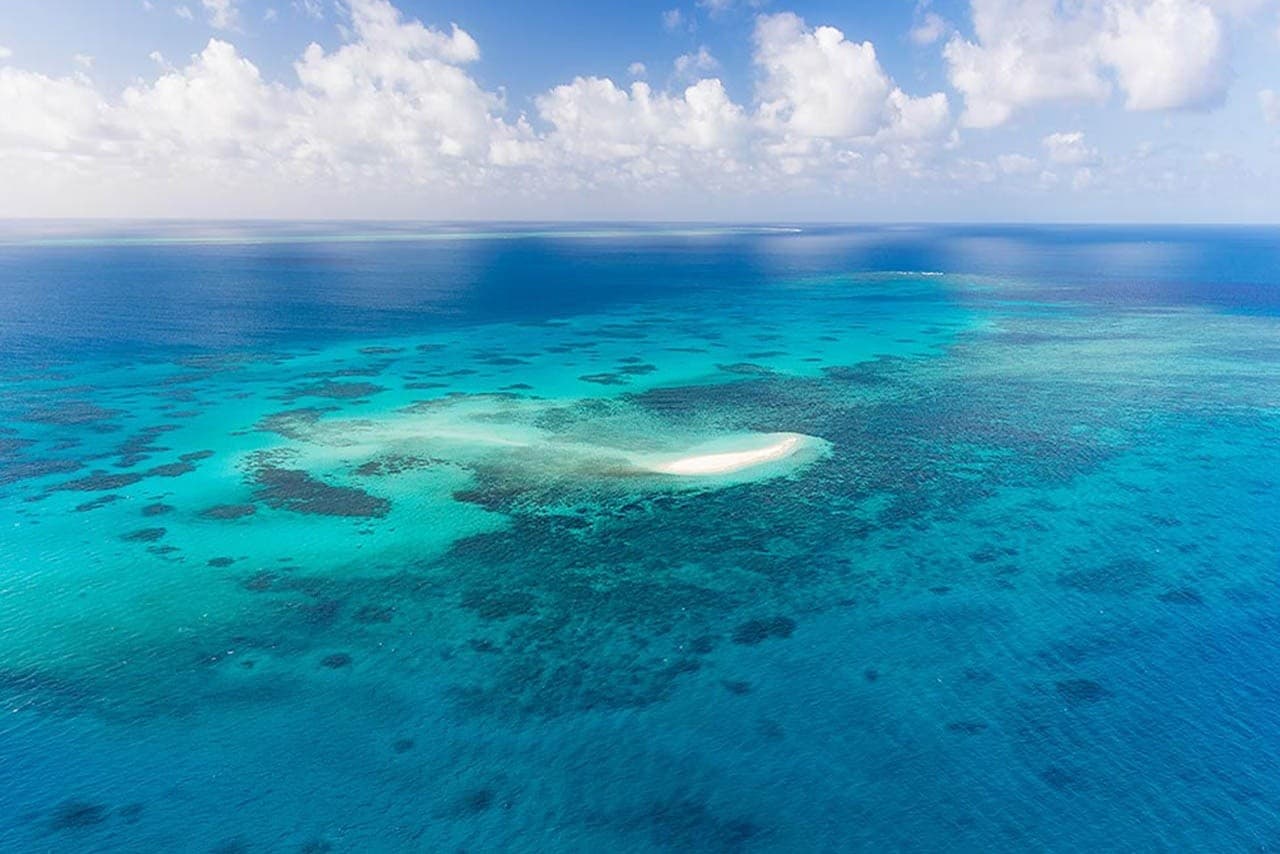 Scenic helicopter flying over dramatic coastal reef and atoll