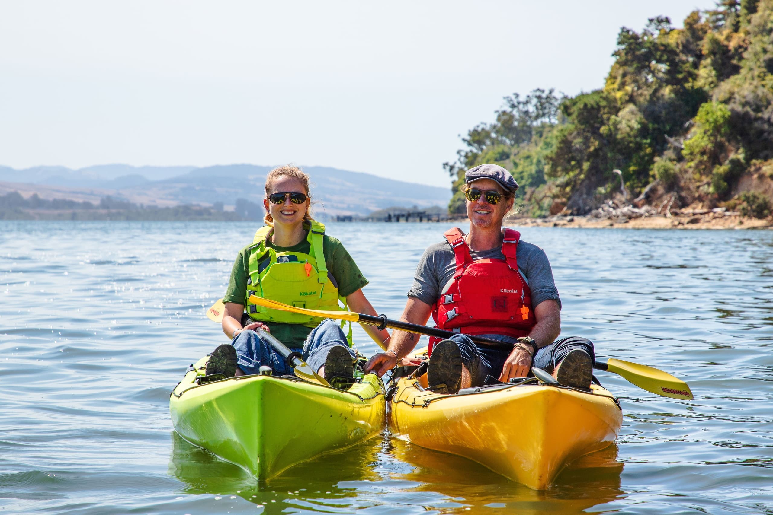 Two kayakers paddling near coastal shoreline on Tomales Bay
