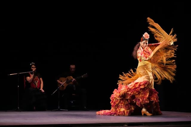 Flamenco dancer performing on stage with musicians in a theater