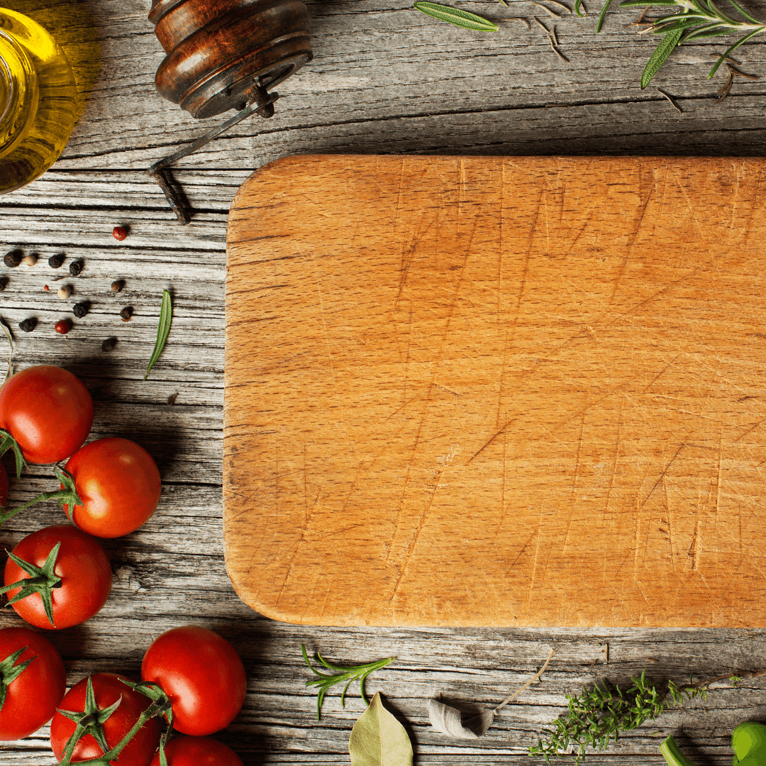 Rustic wooden cutting board with tomatoes and herbs outdoors