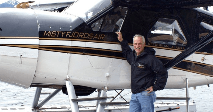 Pilot beside Misty Fjords seaplane on coastal dock, tour operator