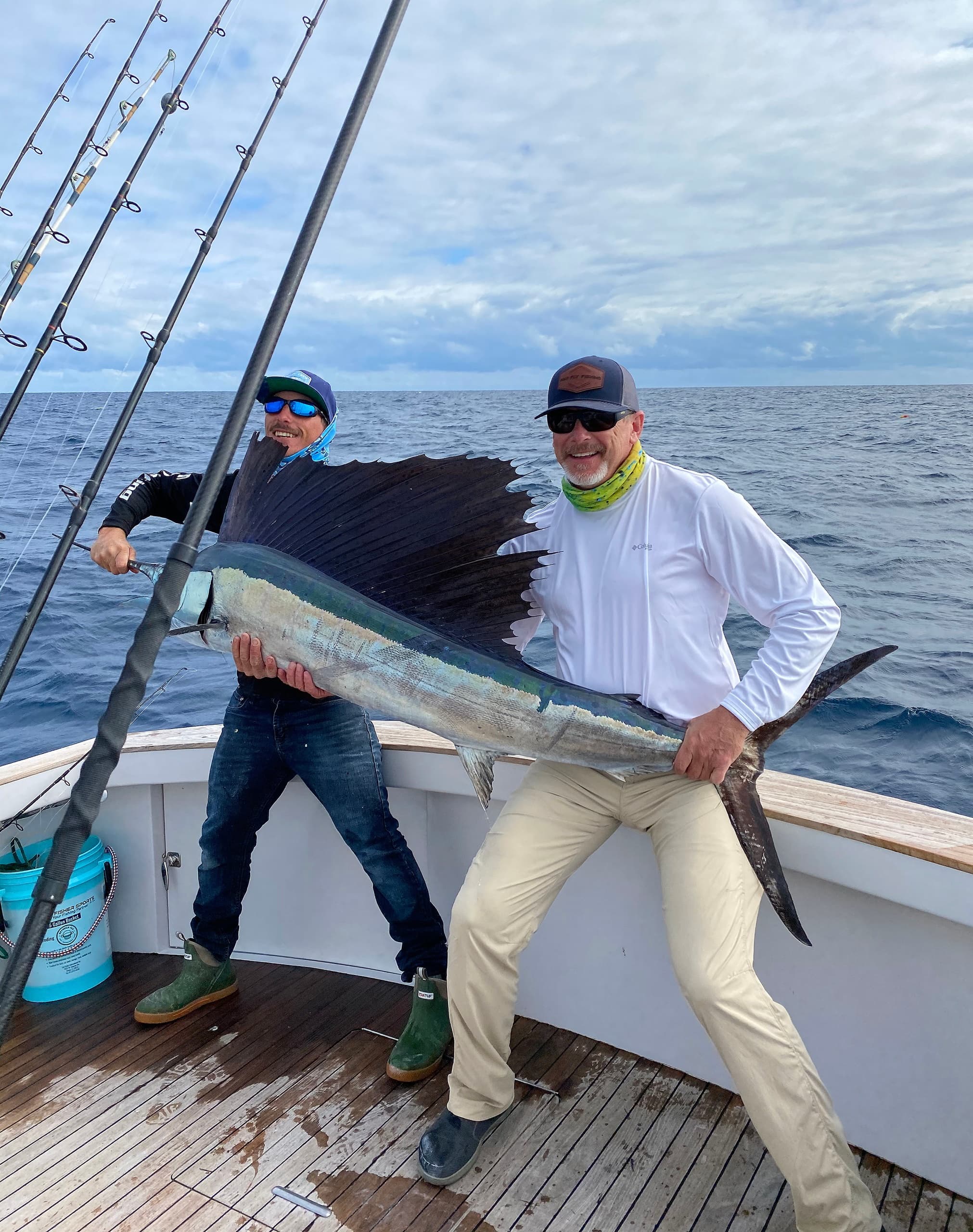 Two anglers posing with a large sailfish on ocean deck