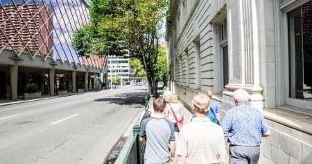 Small group walking tour along a shaded downtown Calgary street