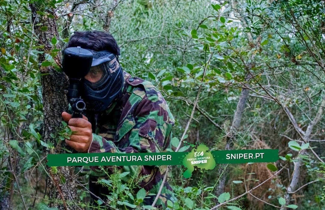 Paintball player in camouflage hiding in dense forest, outdoor game
