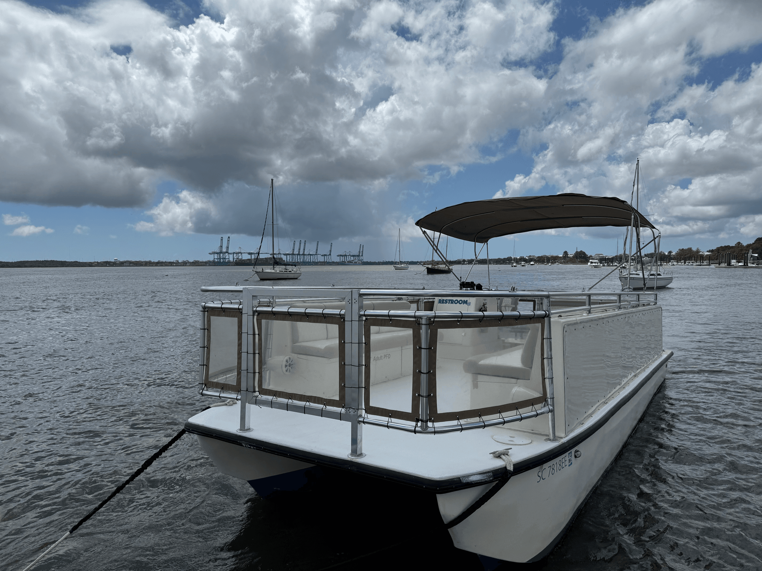 Covered rental pontoon boat docked on coastal harbor