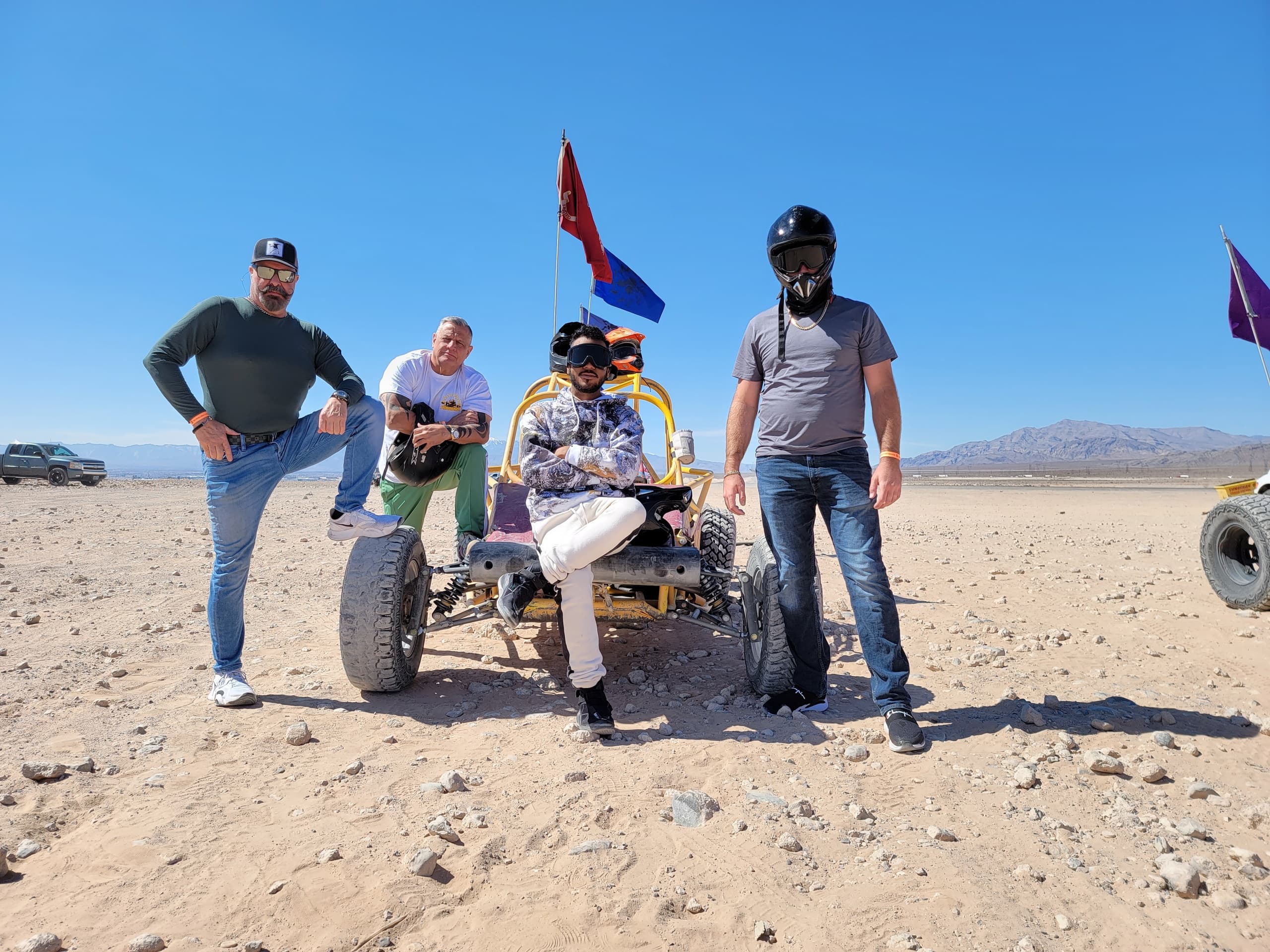 Friends with dune buggy on sandy desert outing with flags