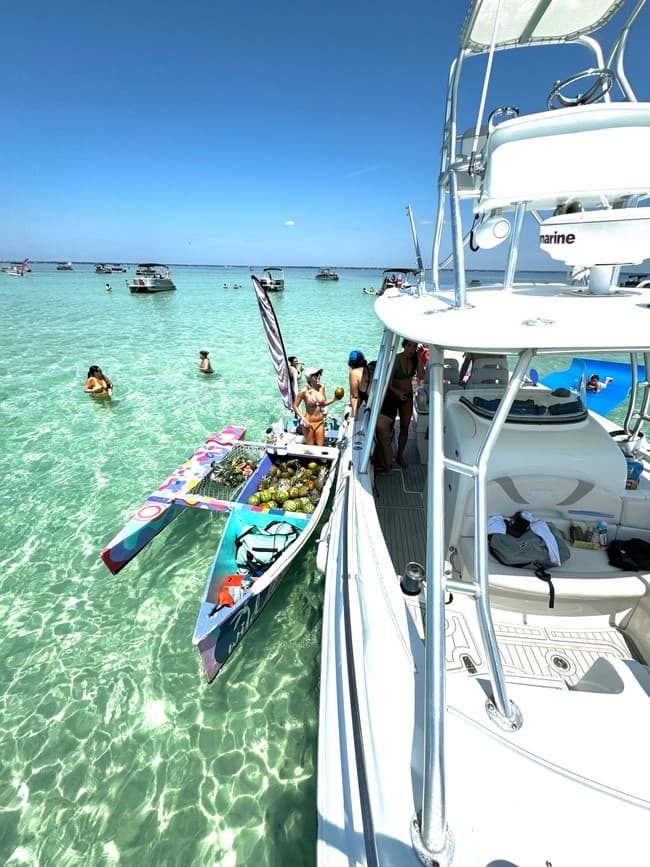 Guests paddleboarding beside yacht in crystal clear shallows
