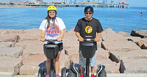 Couple on Segways by coastal jetty with Gulf waters background
