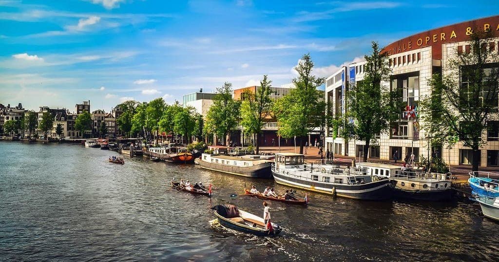 Busy Amsterdam canal with tour boats and city skyline