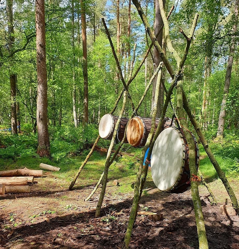 Handcrafted drum installation set among pine forest campsite
