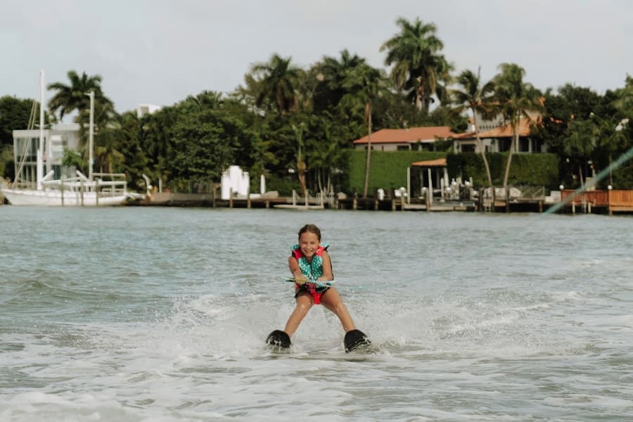 Waterskier cutting across bay with palm-lined shoreline nearby