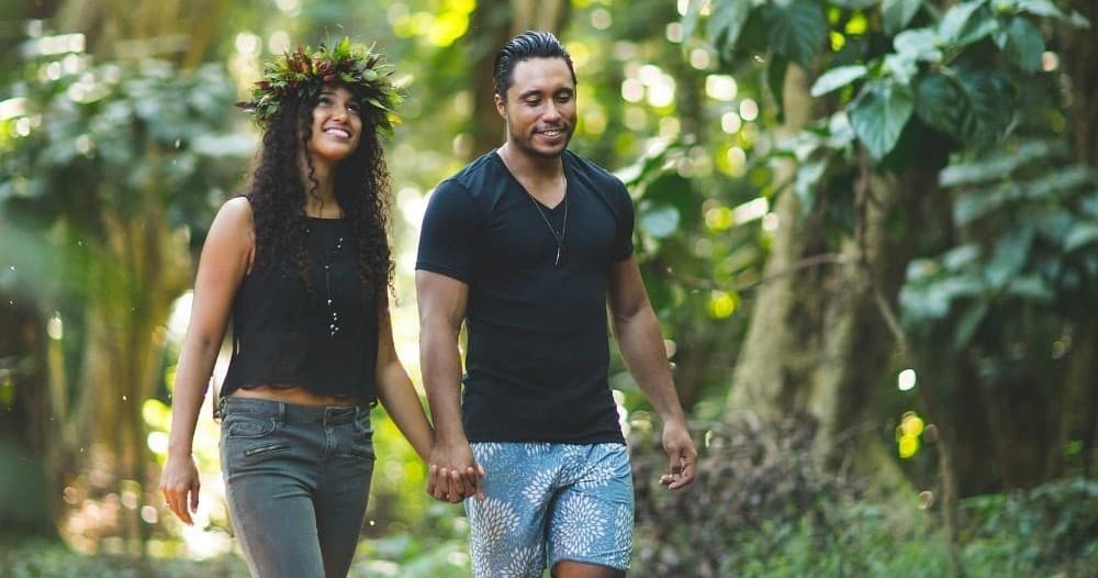 Couple hiking hand-in-hand through shaded tropical forest trail