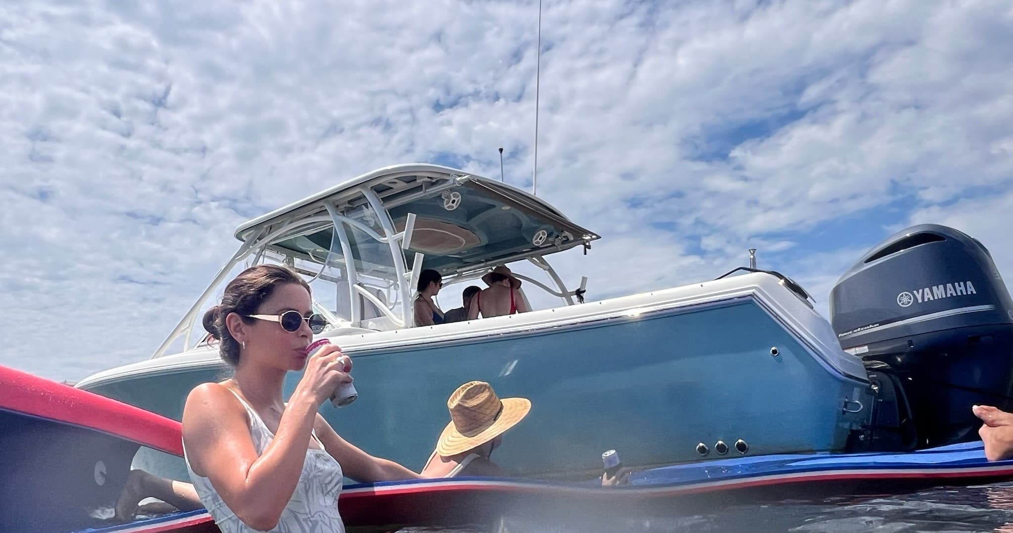 People socializing on powerboat under bright blue sky near dock