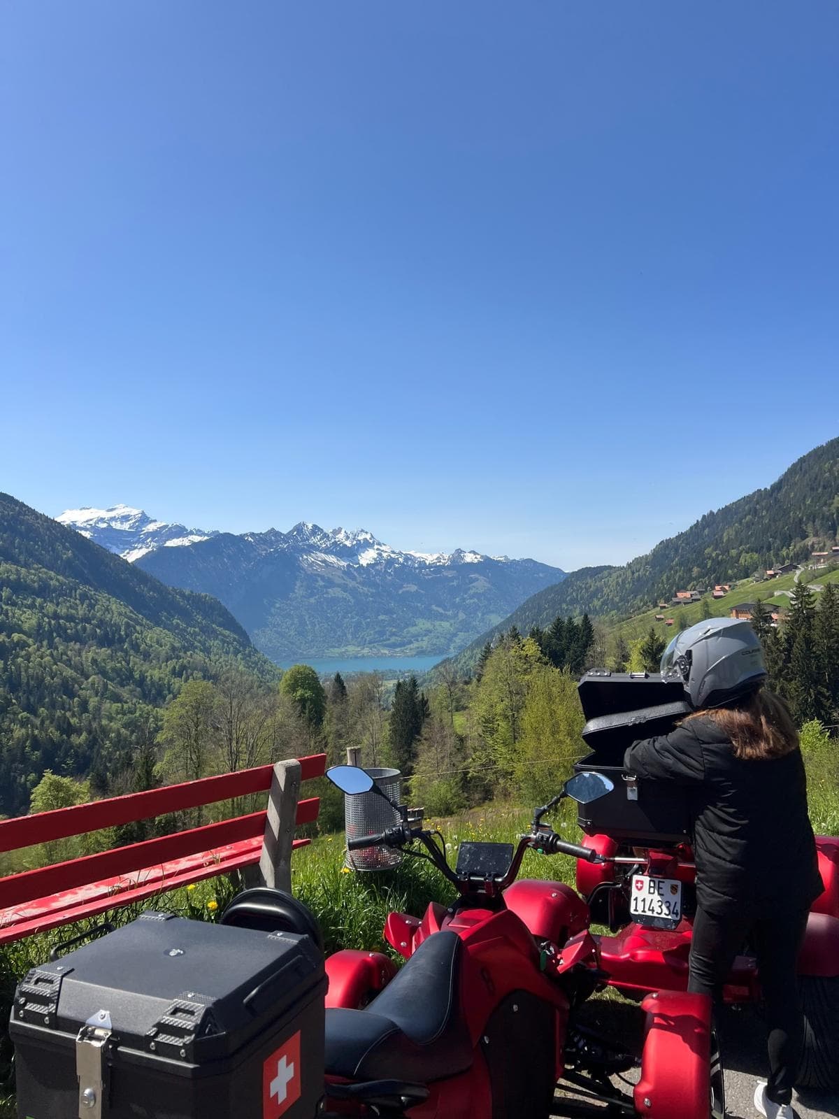 Red quads parked overlooking deep alpine valley and mountain vista