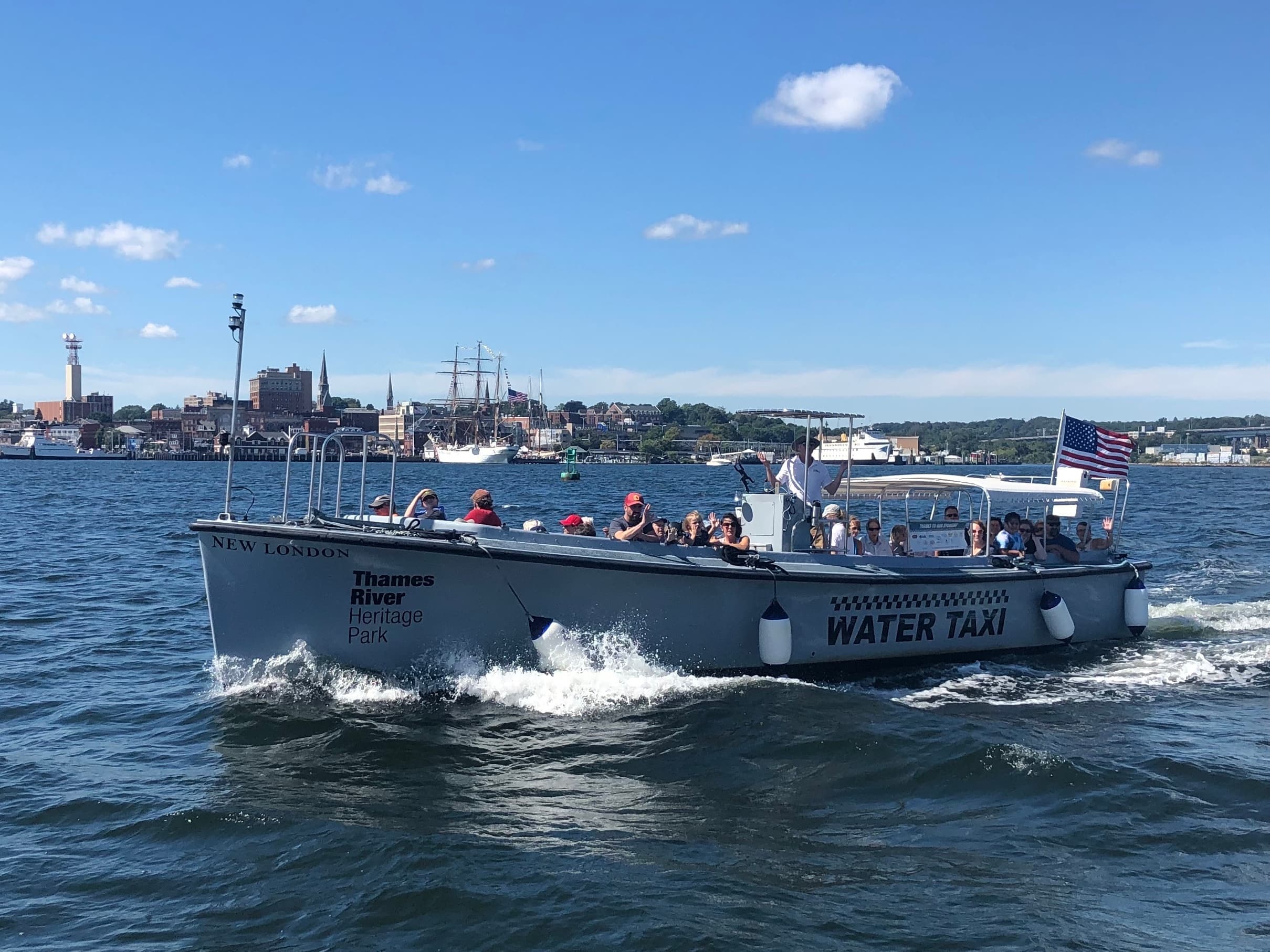 Water taxi speeding across Thames River with city skyline