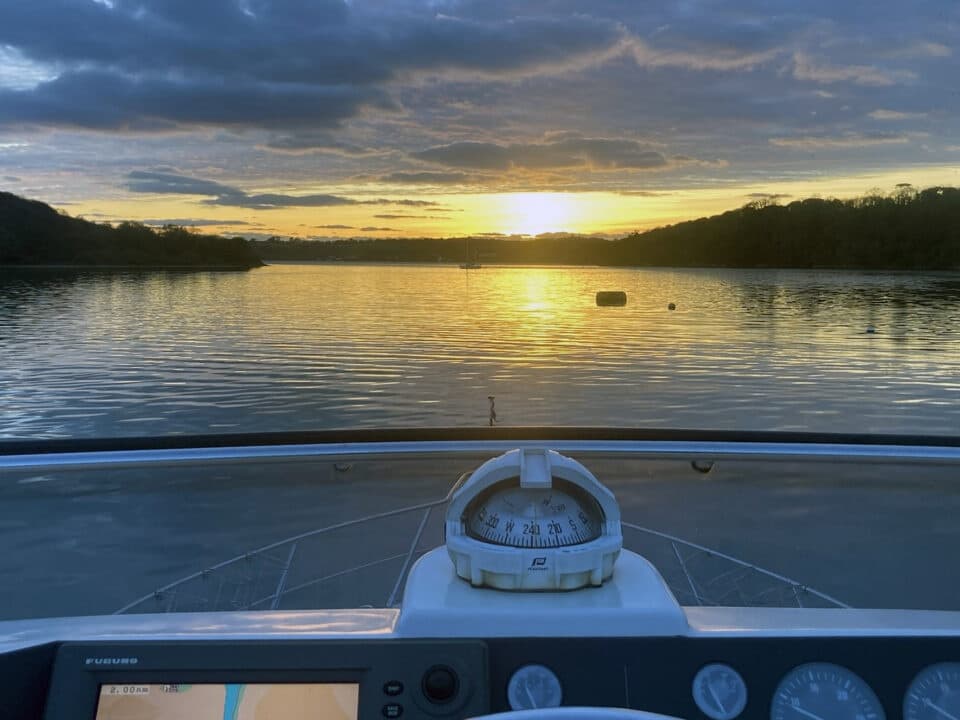 Sunset from yacht bow over calm estuary during evening cruise