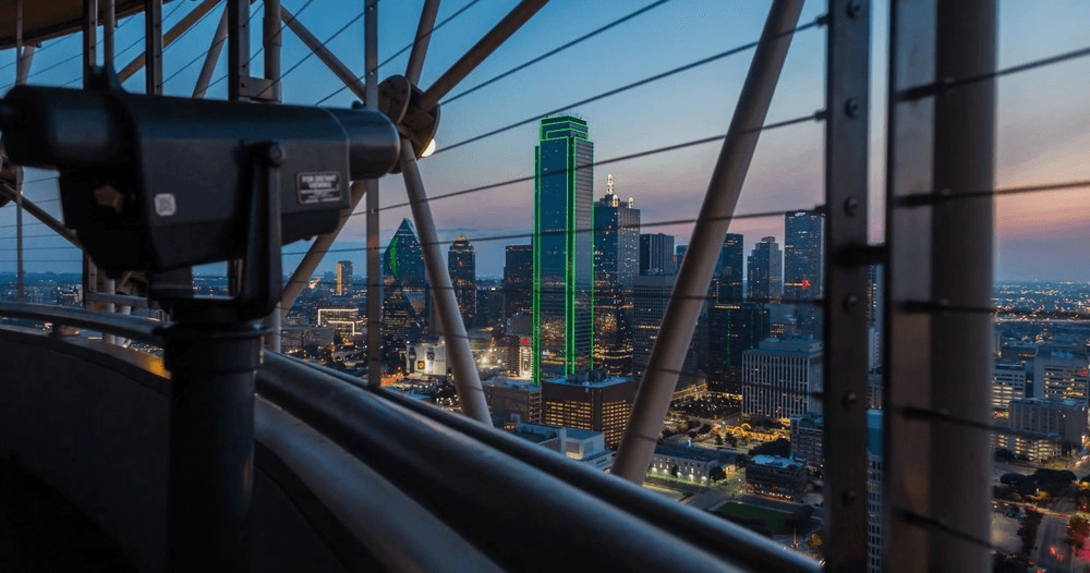 City skyline framed by Reunion Tower railings at dusk