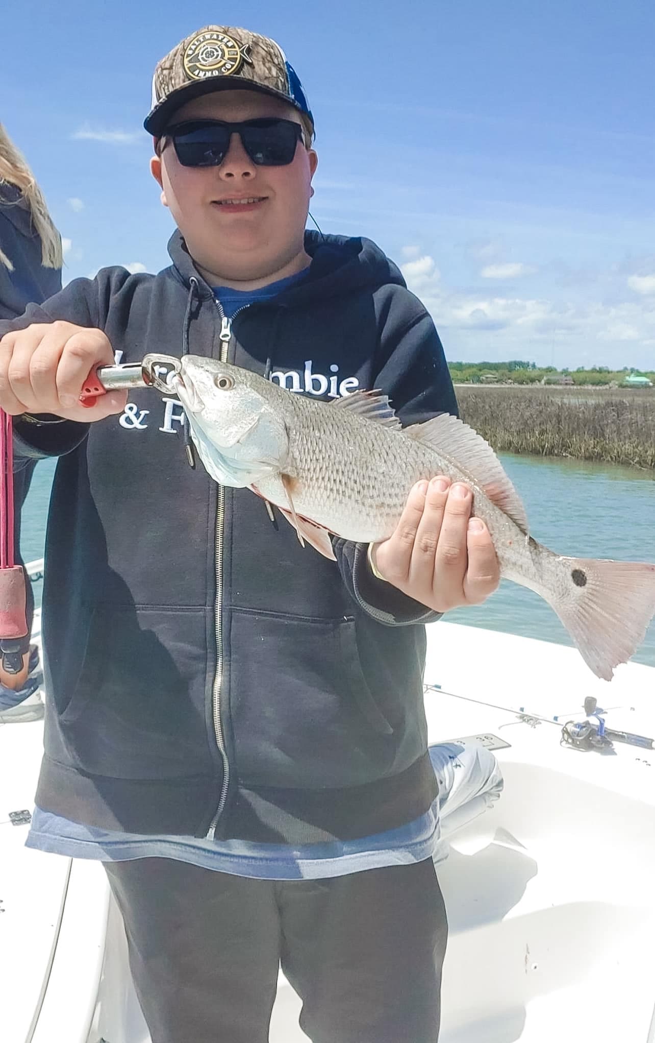 Angler holding speckled trout on boat, near coastal waters
