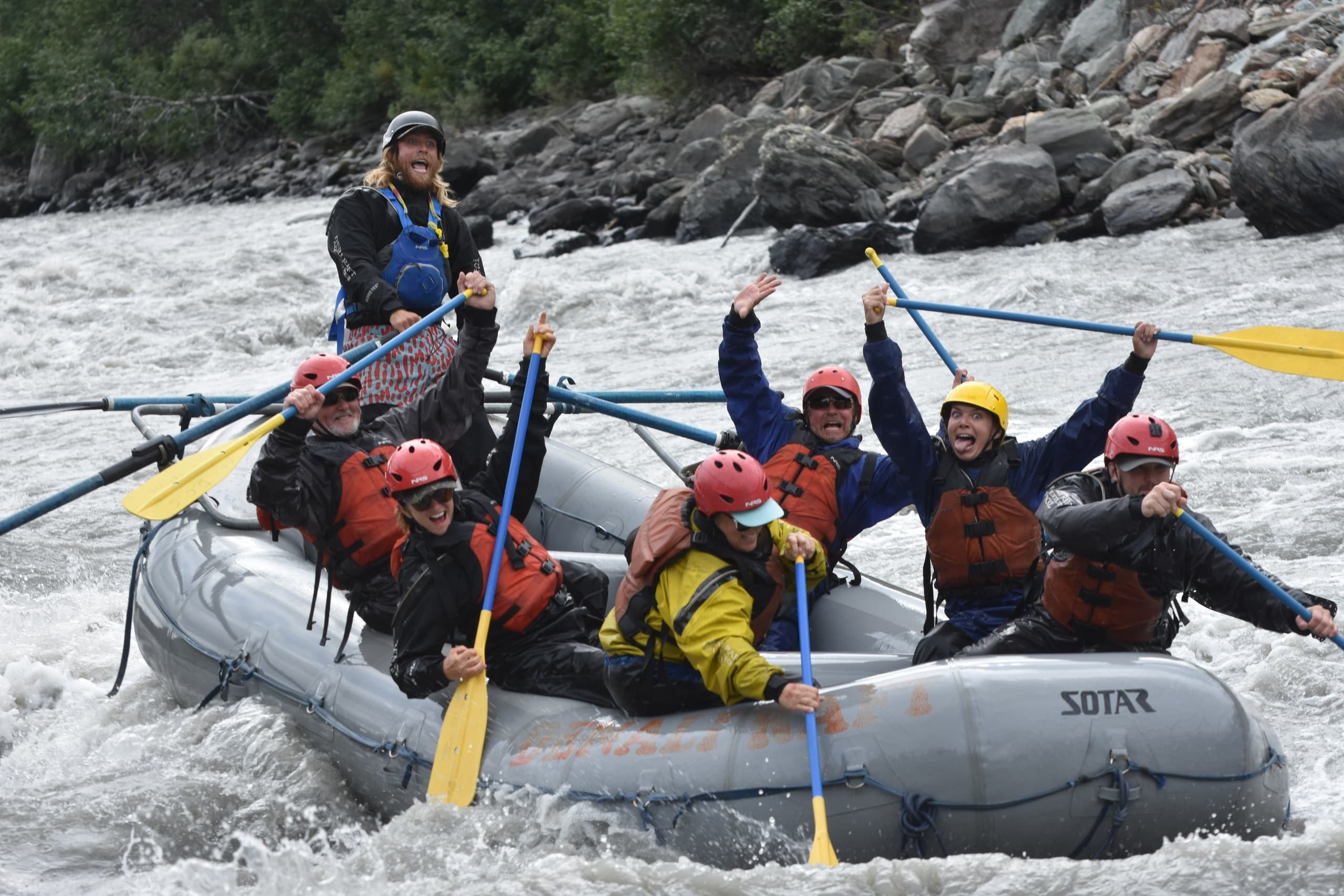 Rafting crew cheering with paddles on turbulent river