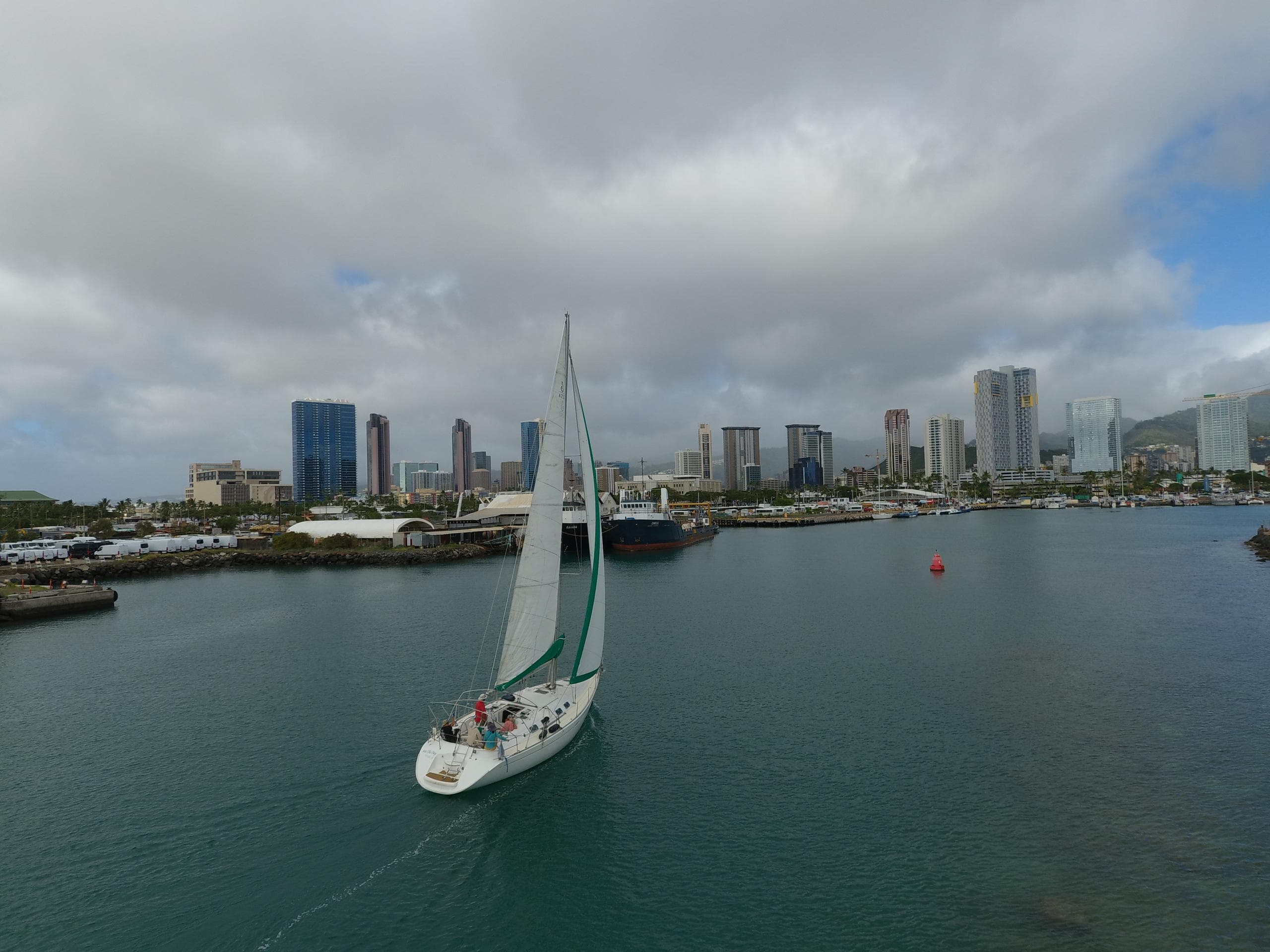 Sailboat approaching Honolulu harbor with skyline backdrop