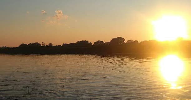 Sunset over calm lake shoreline with golden reflections