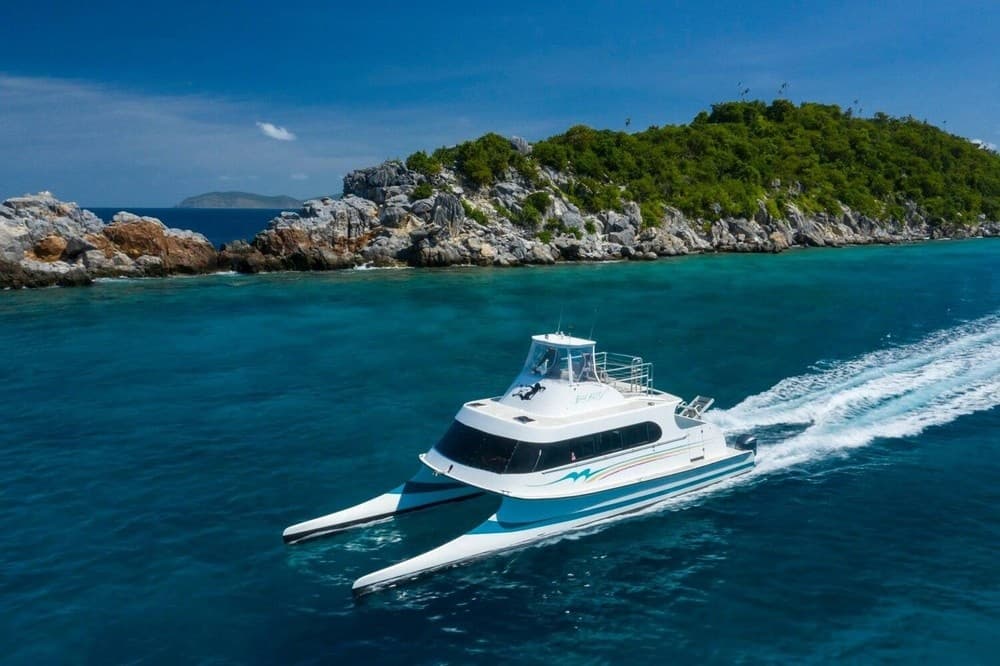 Powerboat cruising past rocky island coastline in clear ocean