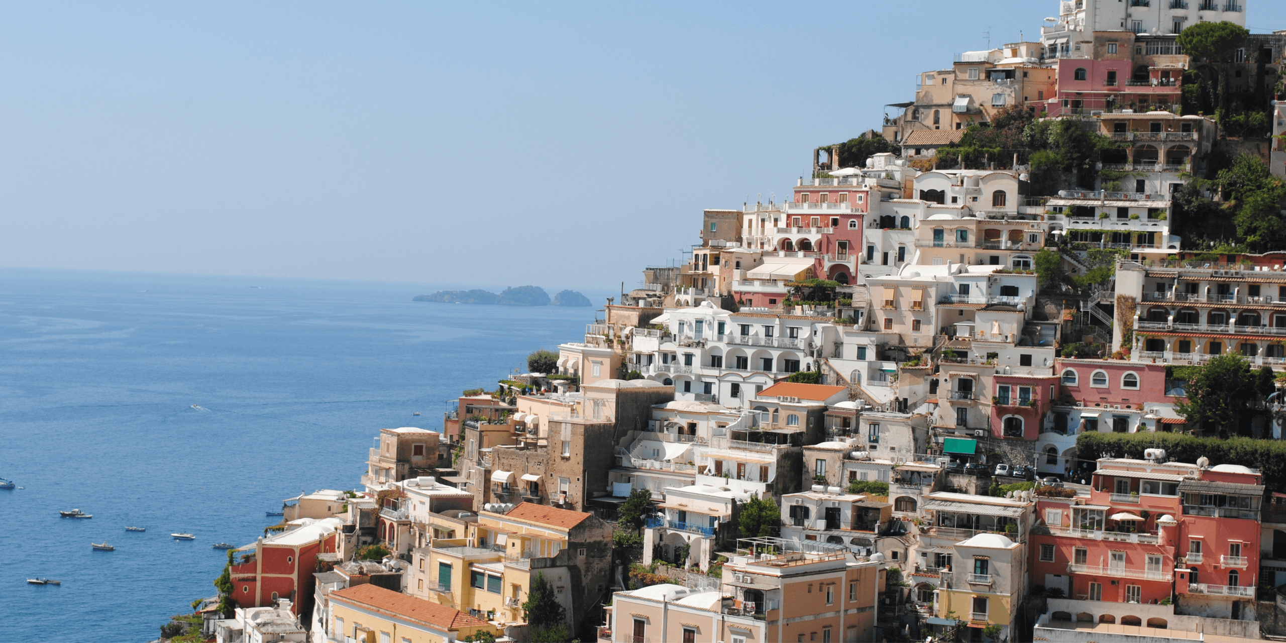 Positano hillside buildings cascading to sea on sunny day