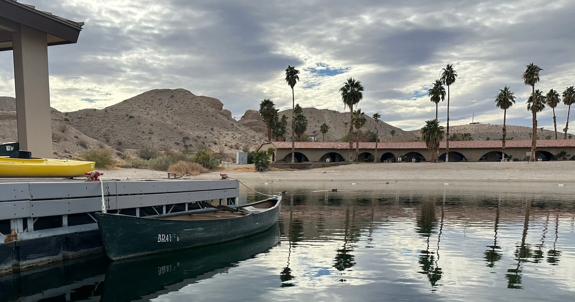 Canoe moored at palm-lined marina with mountain backdrop