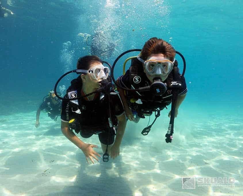 Two scuba divers exploring shallow tropical reef near shore