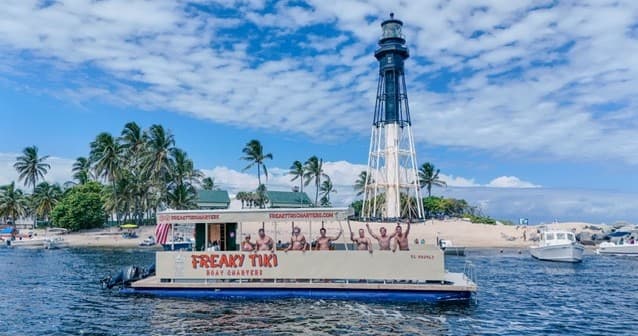 Boat charter passing a lighthouse on bright tropical coast