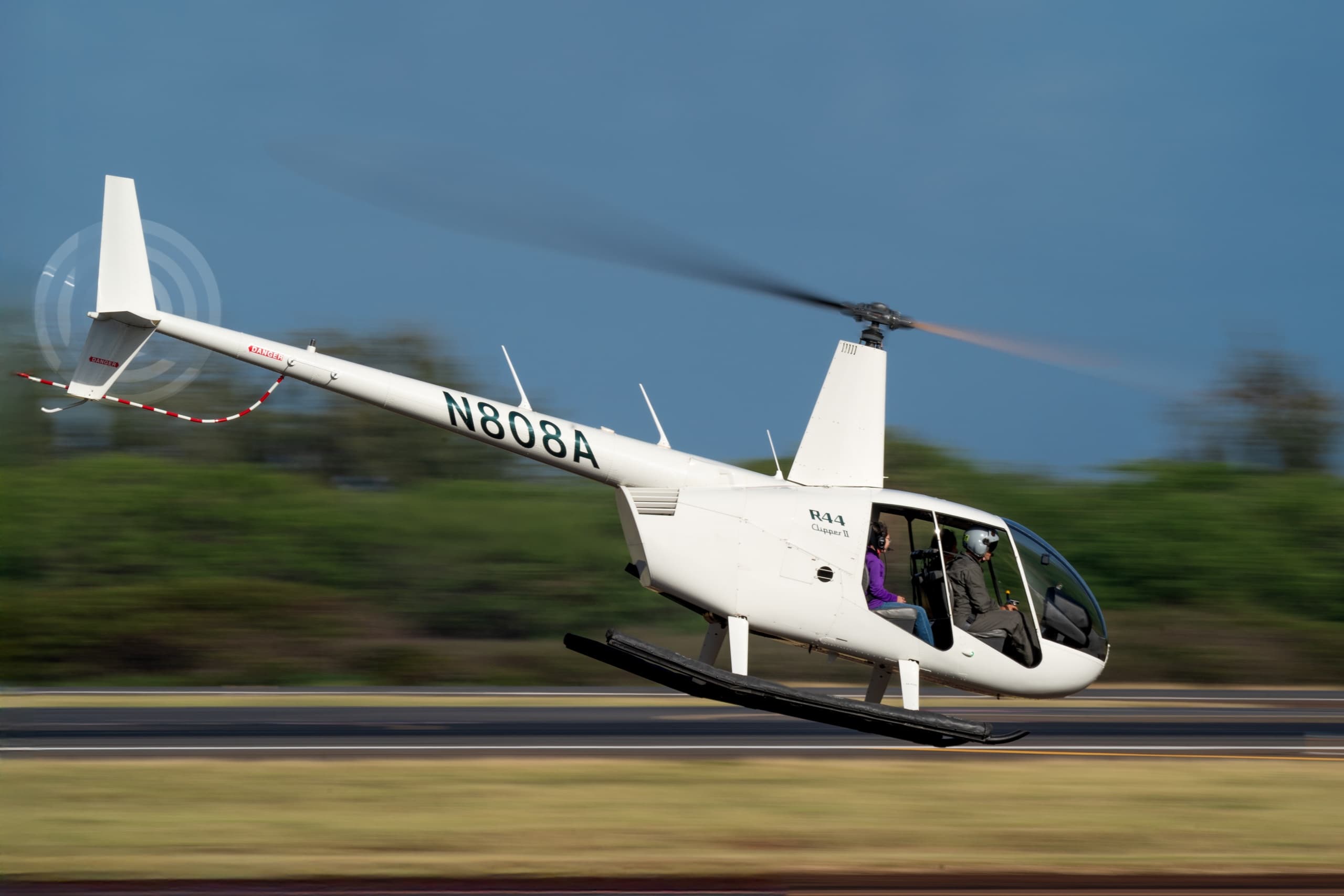 Low-altitude helicopter skimming runway in tropical air tour