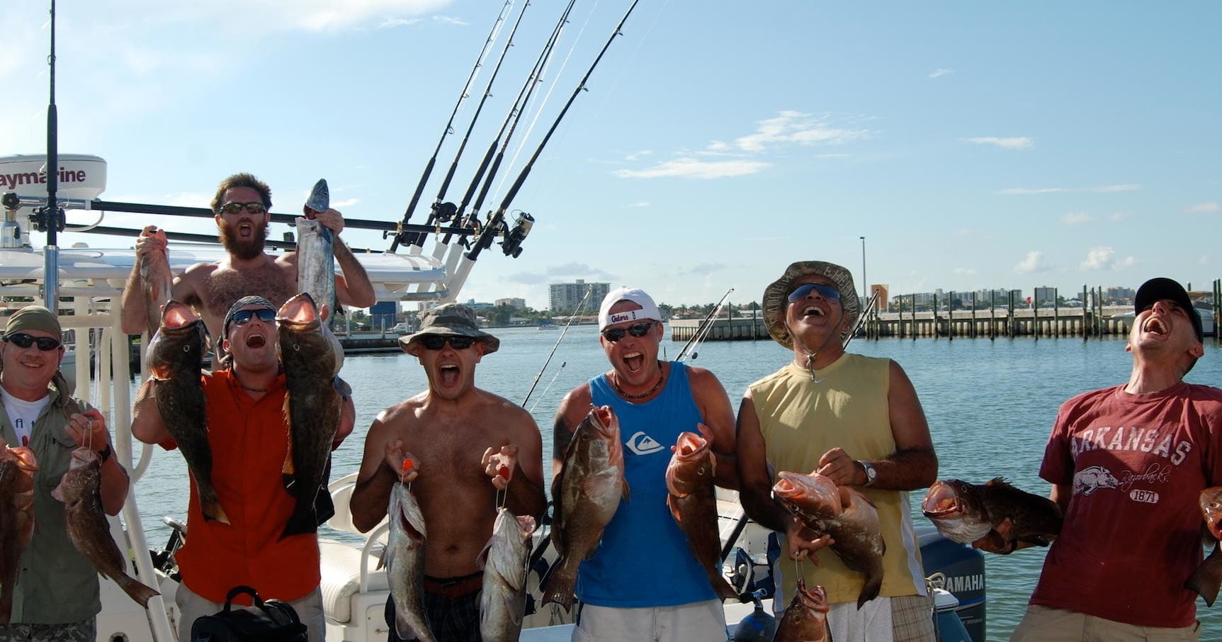 Anglers posing with mixed reef fish on boat at marina dock