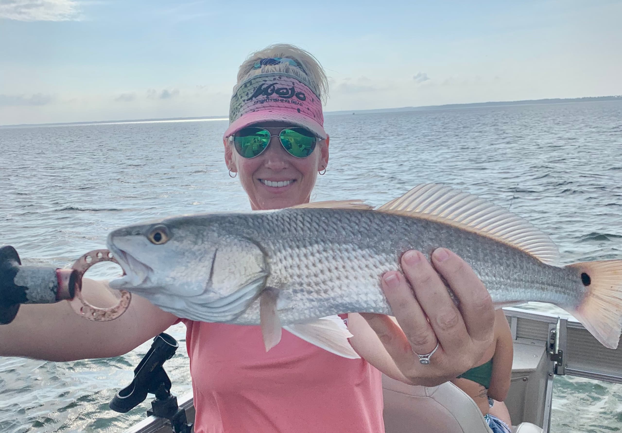 Angler holding redfish on boat, inshore saltwater fishing trip