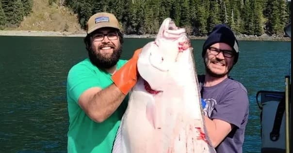 Anglers holding giant halibut on boat during coastal fishing trip
