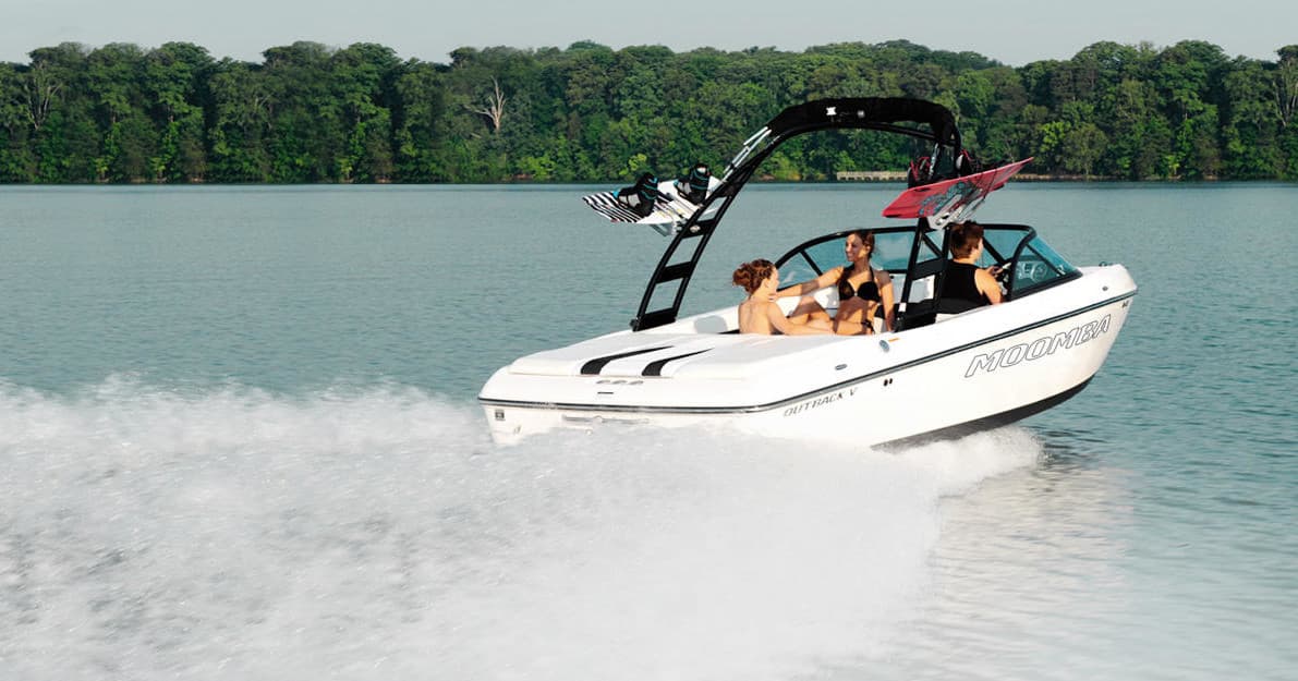 Speedboat cutting through open lake water with tree-lined shore