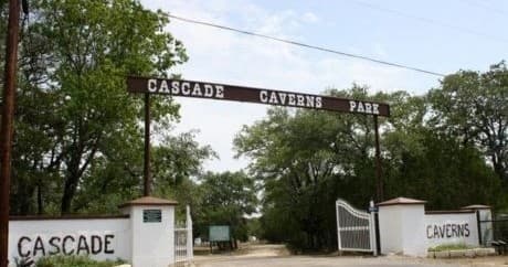 Cascade Caverns park entrance sign and gated drive under trees