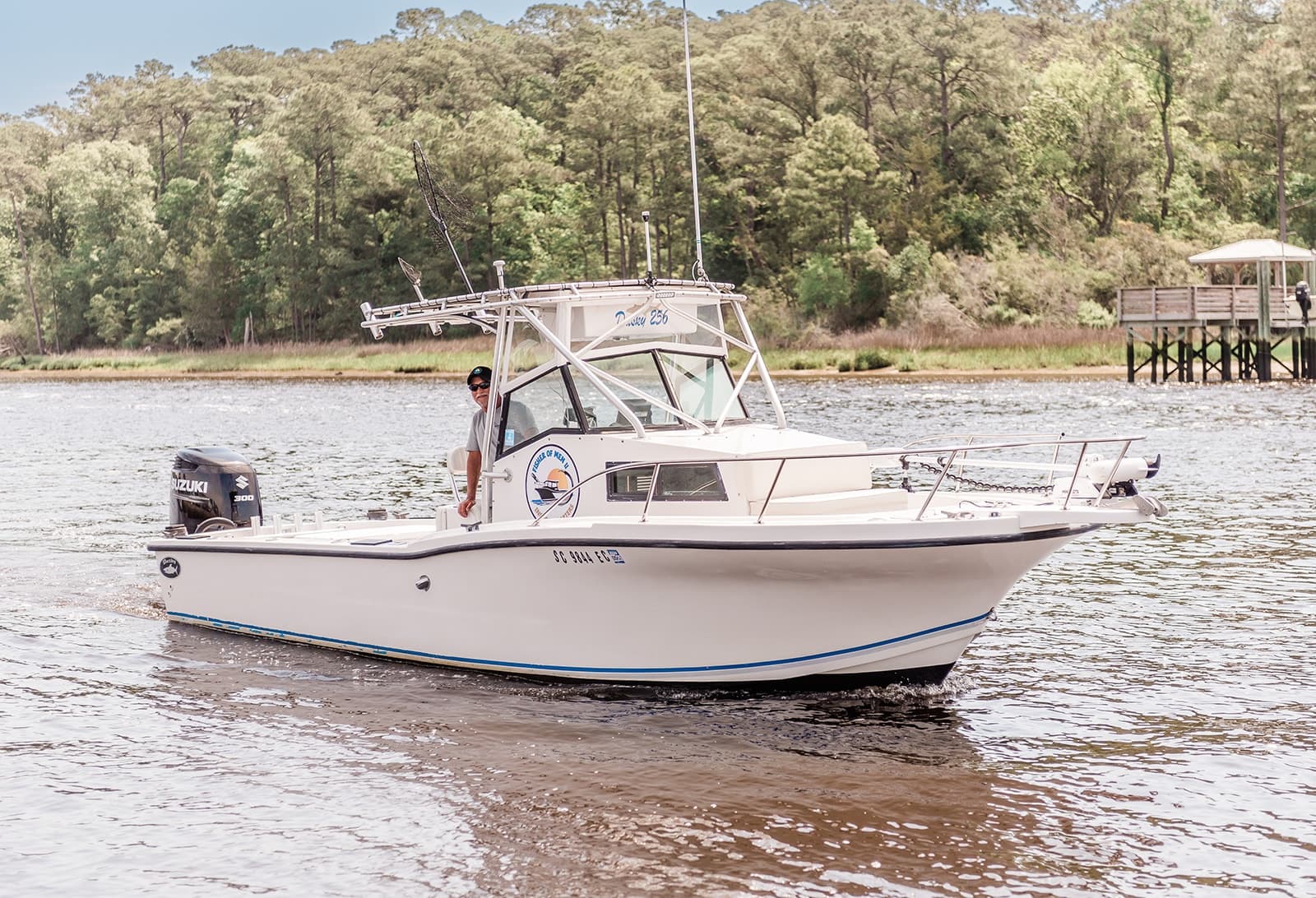 Inshore fishing charter boat cruising coastal river with angler