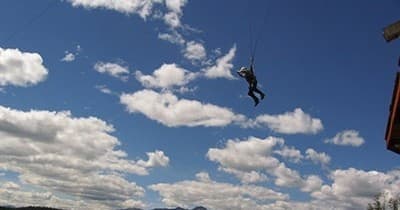 Person ziplining across blue sky over mountainous landscape