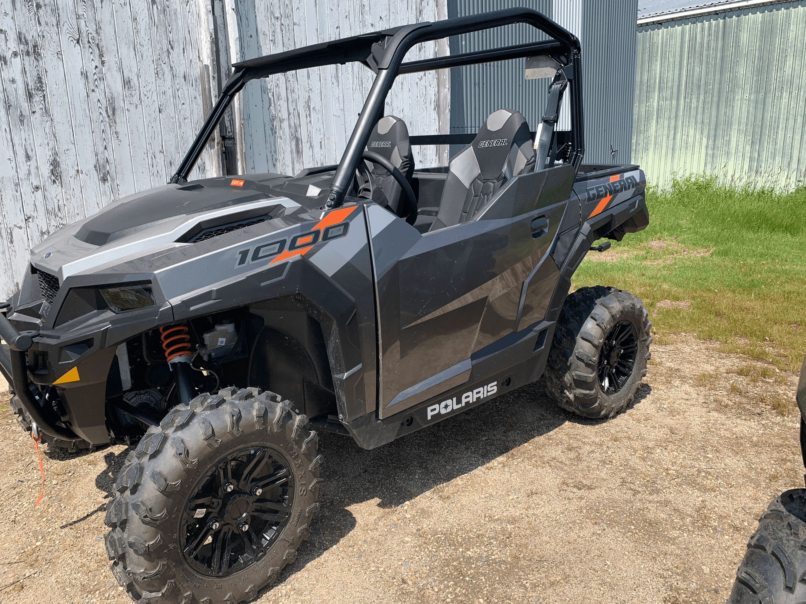 Polaris UTV parked on dirt lot near barn, off-road vehicle