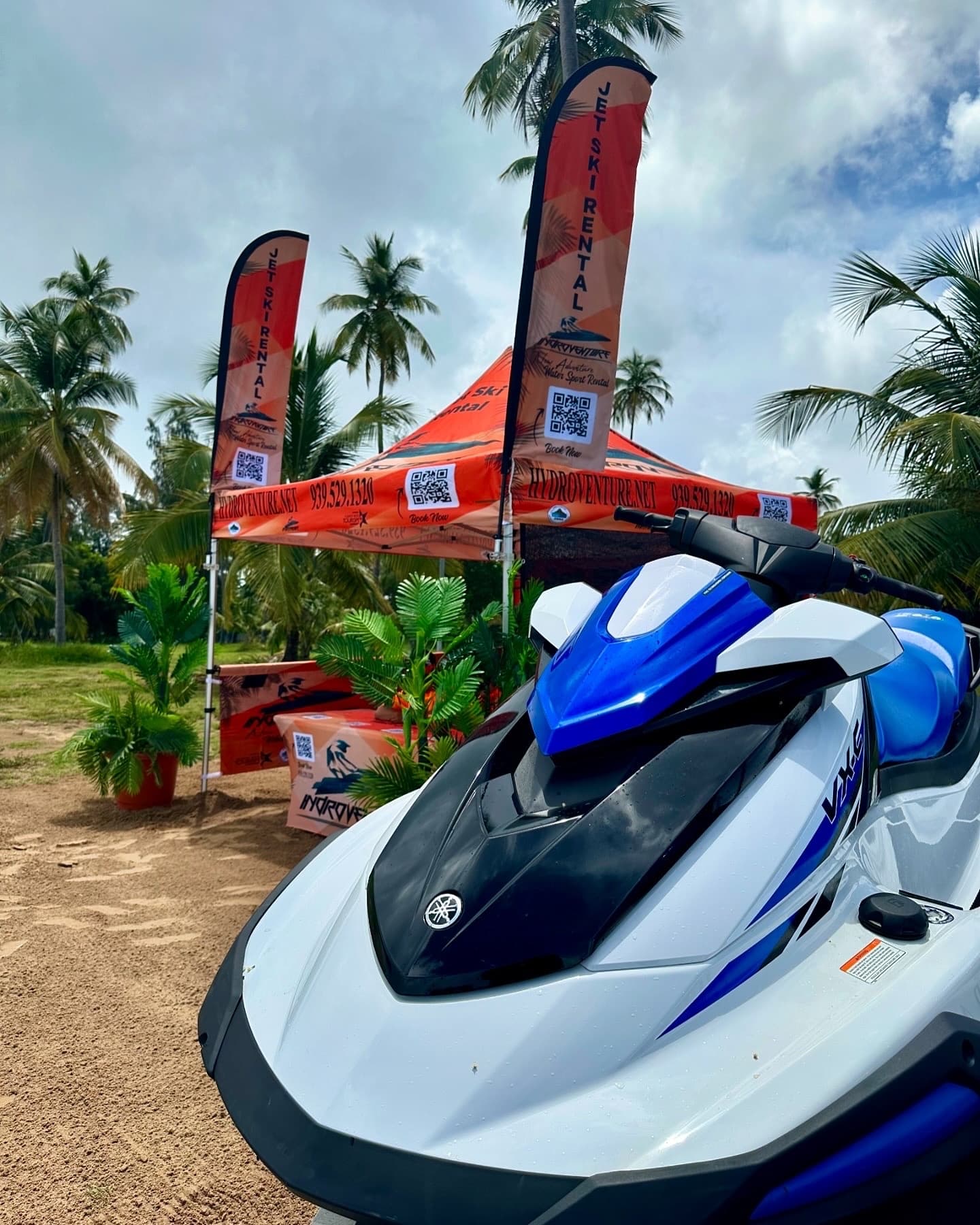 Blue jet ski parked on sandy beach with palm trees backdrop
