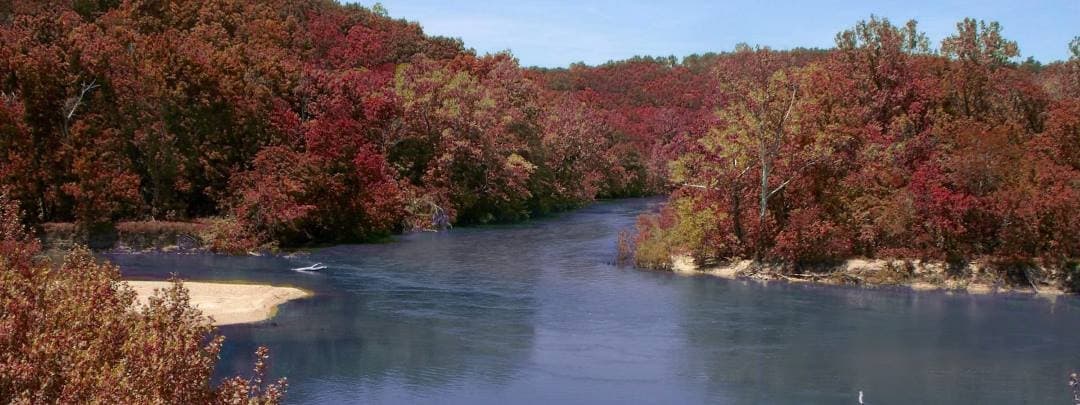 Autumn river panorama with red foliage along sandstone banks