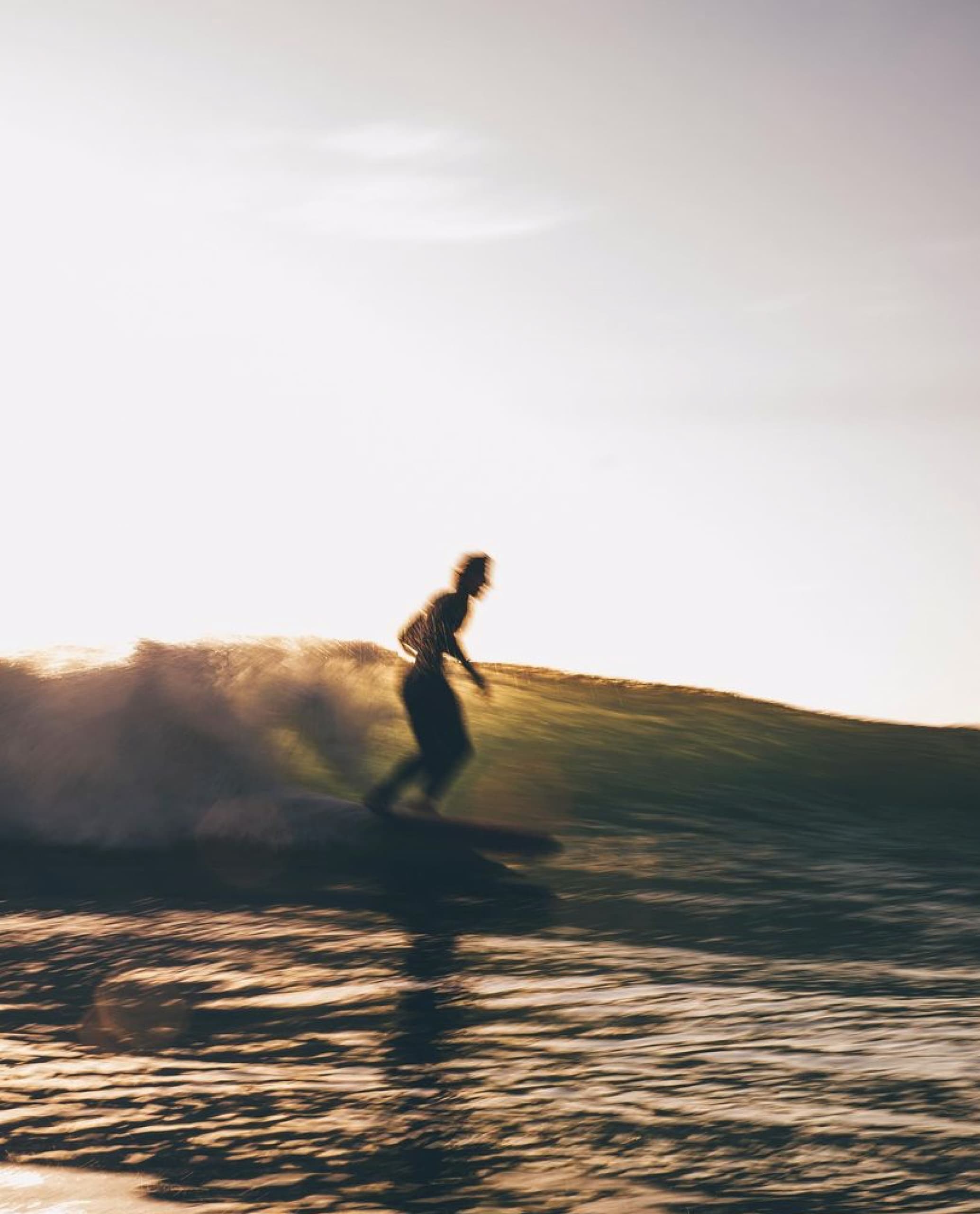 Surfer riding wave off Basque coast at golden hour