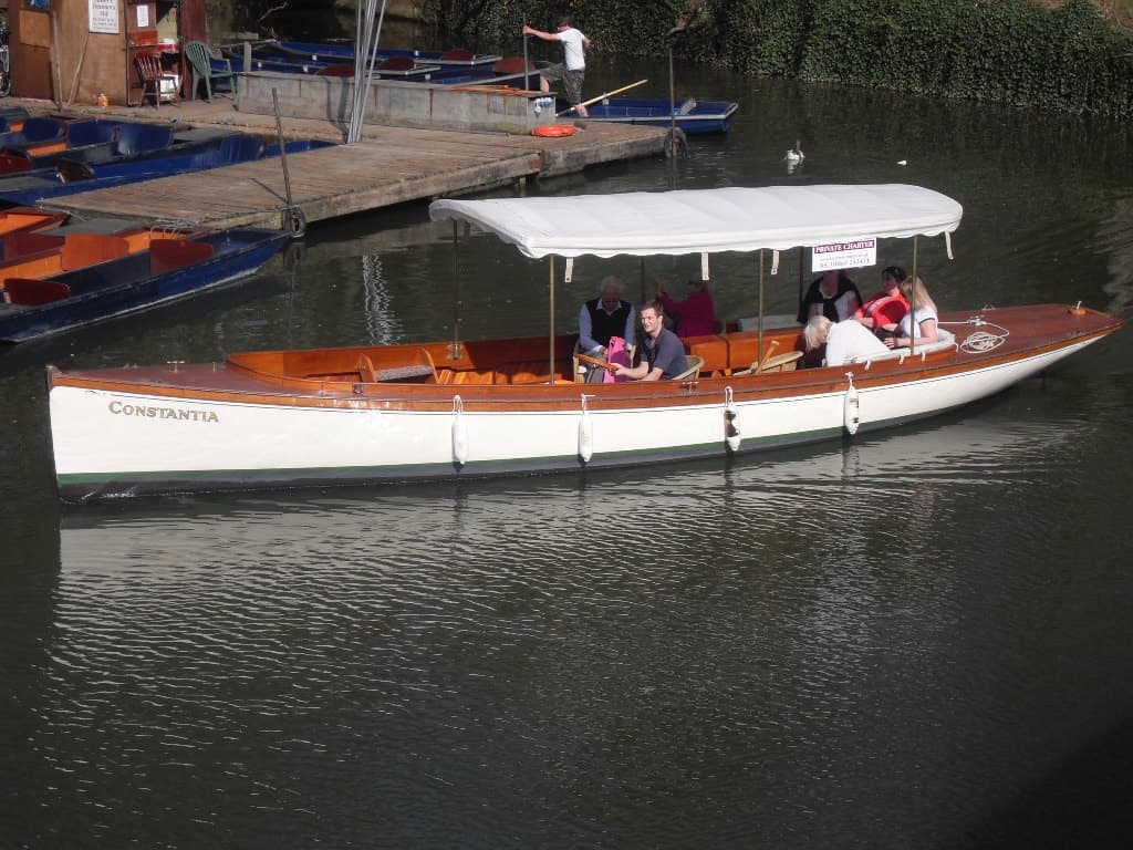 Wooden river launch with canopy carrying passengers on calm river