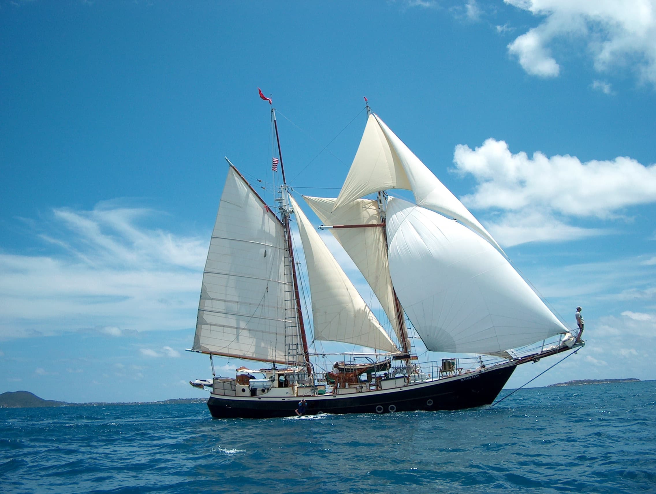 Classic schooner sailing on open ocean with clear blue sky