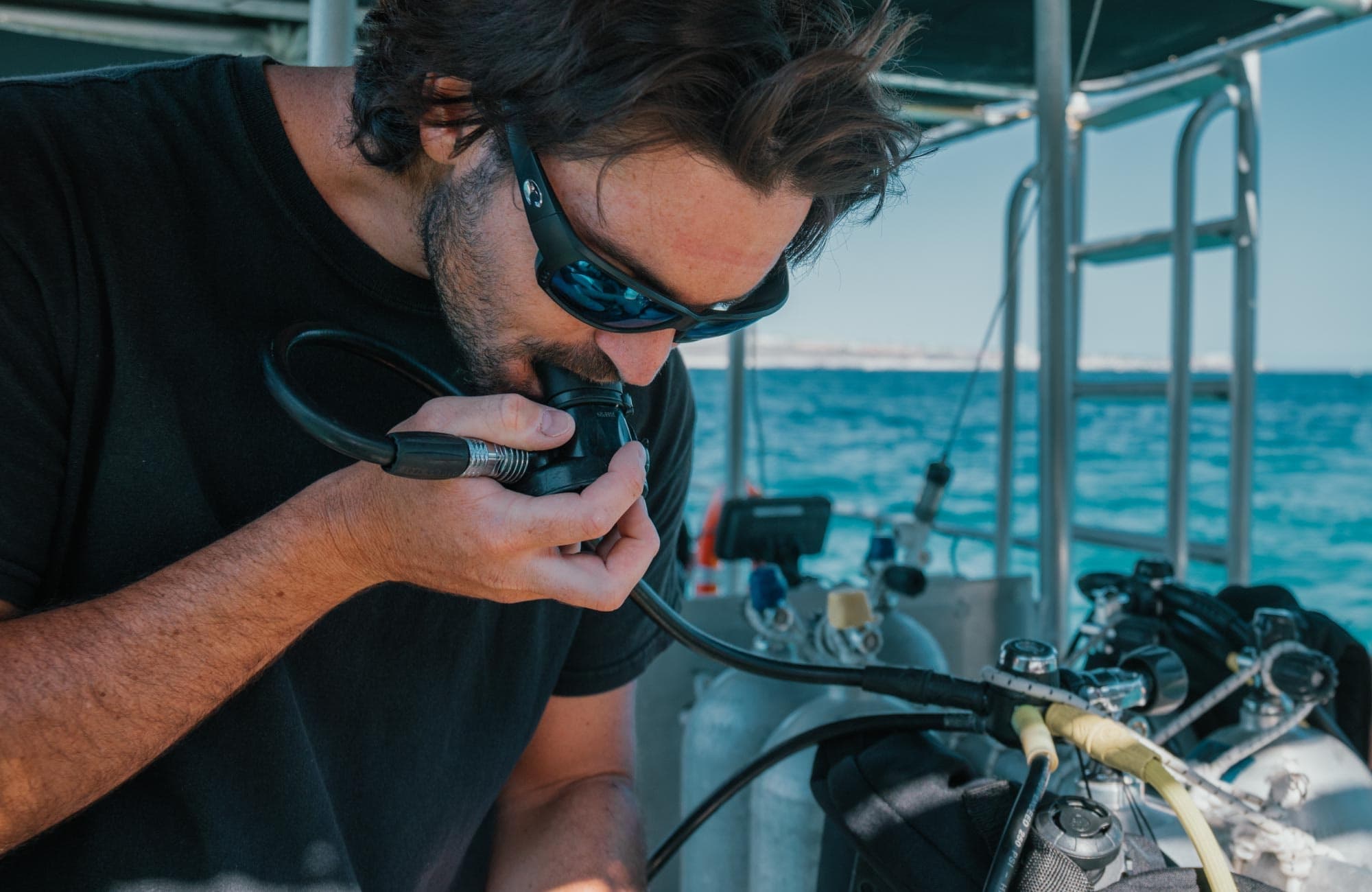 Diver checking regulator aboard boat before Cabo scuba dive excursion