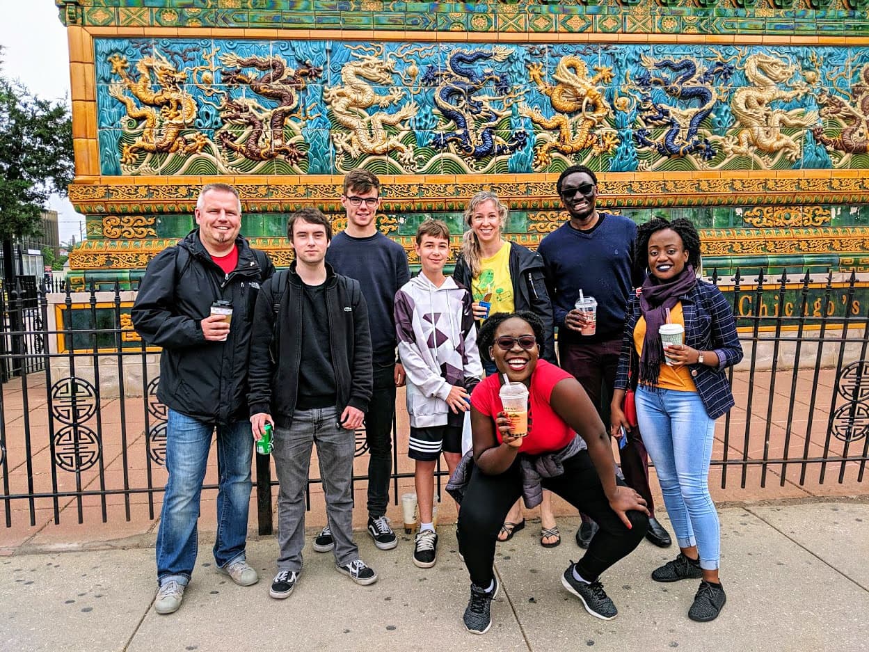 Walking tour group posing by colorful mosaic mural in Chicago