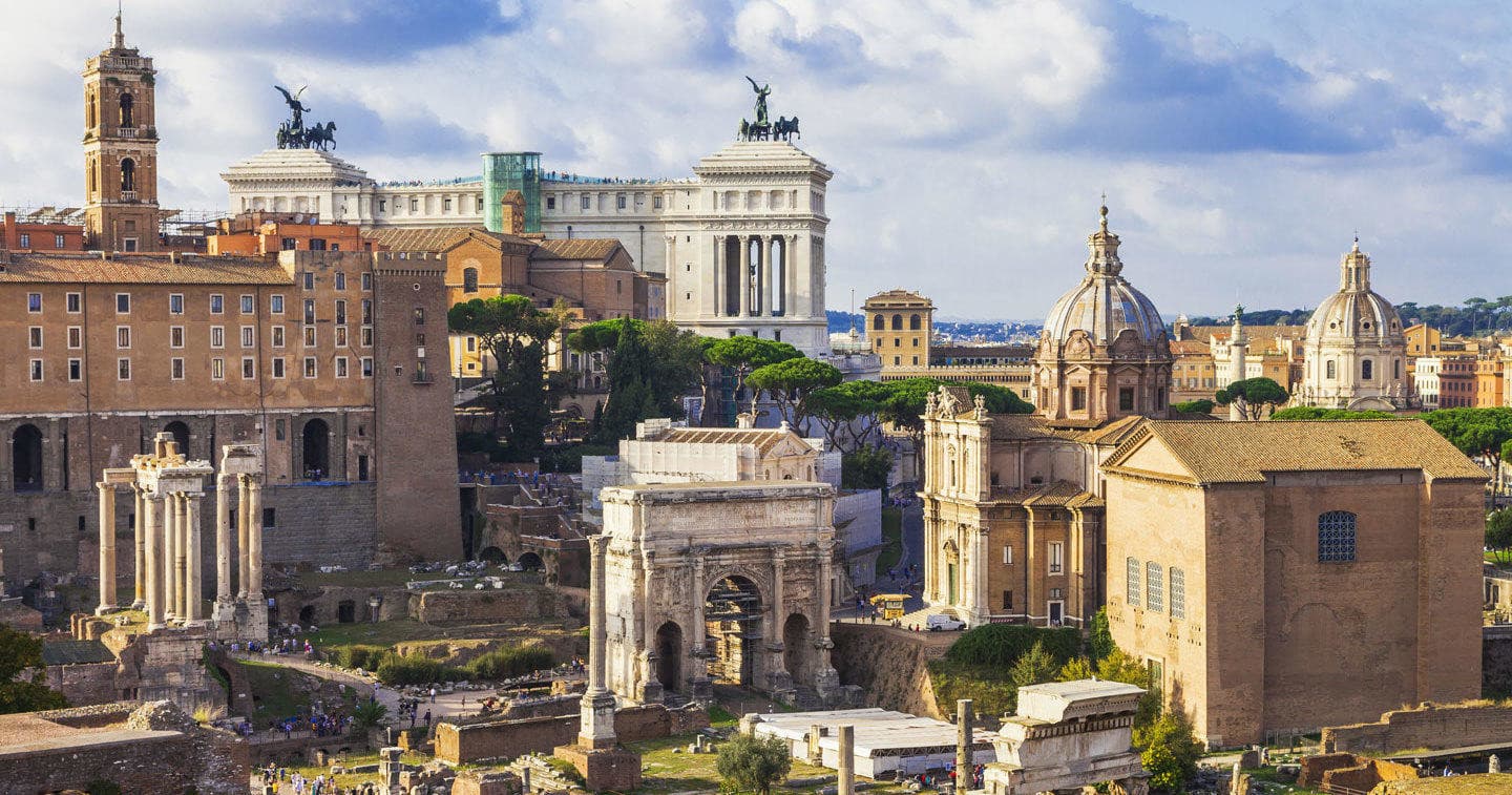 Wide panorama of Roman Forum archaeological ruins under blue sky