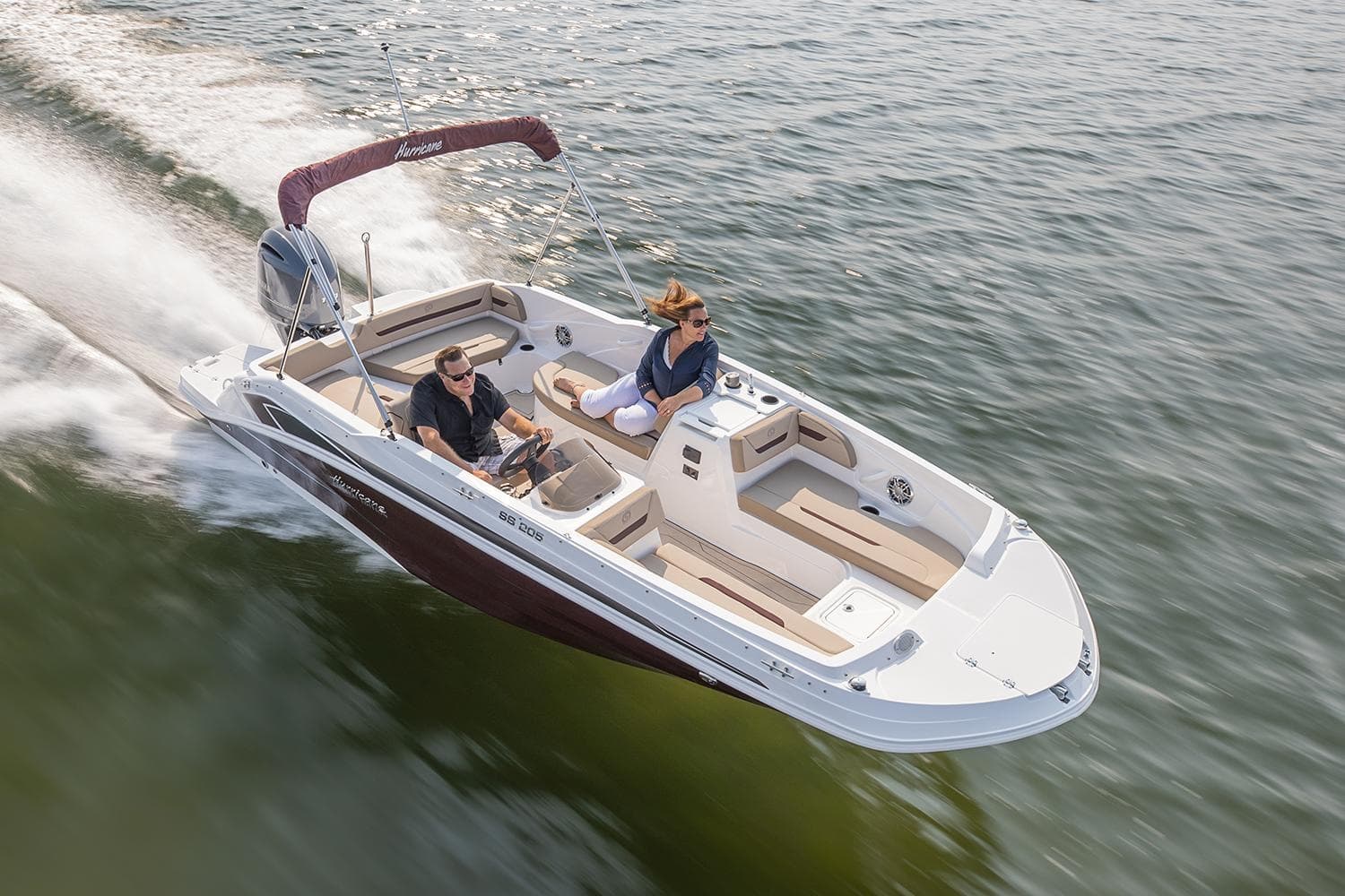 Couple navigating bowrider speedboat across open lake waters